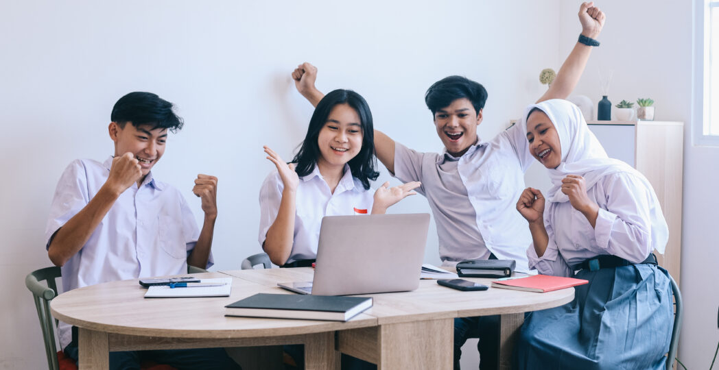 group-multiethnic-asian-students-school-uniform-looking-laptop-desk-celebrating-success-1048x540